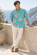 Man wearing the Engraved Hummingbird Garden Resort Shirt in Turquoise Blue on a coastal terrace